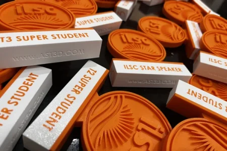 Medalhas personalizadas em impressão 3D para premiação de estudantes da escola de inglês ILSC, produzidas em material plástico laranja.